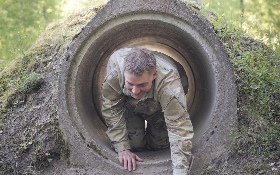 The head and arms of a crawling soldier are seen emerging from one end of a tunnel.