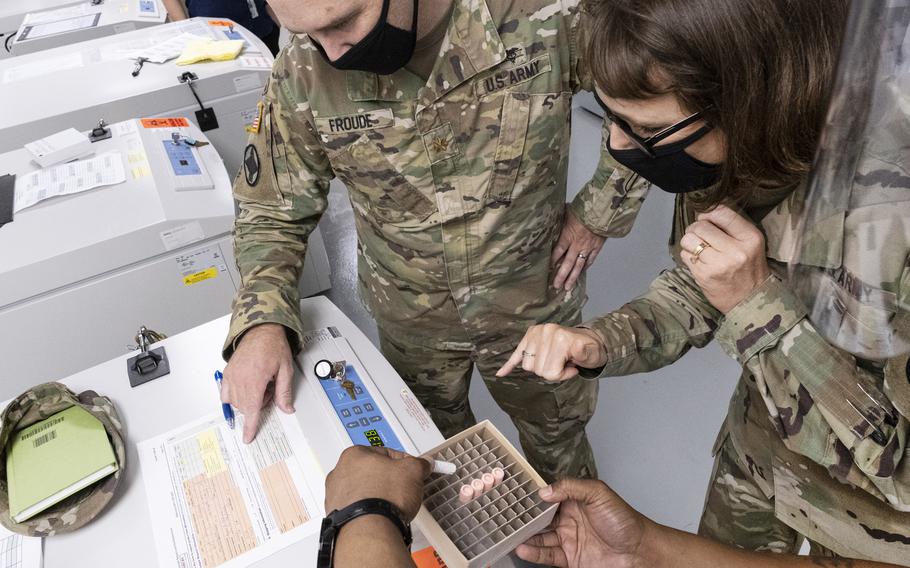 From a single small vial, the manufacture of the Walter Reed Army Institute of Research COVID-19 vaccine begins in August 2020. Right to left are Col. Deydre Teyhen, Commander of WRAIR, and Maj. Jeffrey Froud, Director of the WRAIR Pilot Bioproduction Facility (PBF) Quality Assurance team.