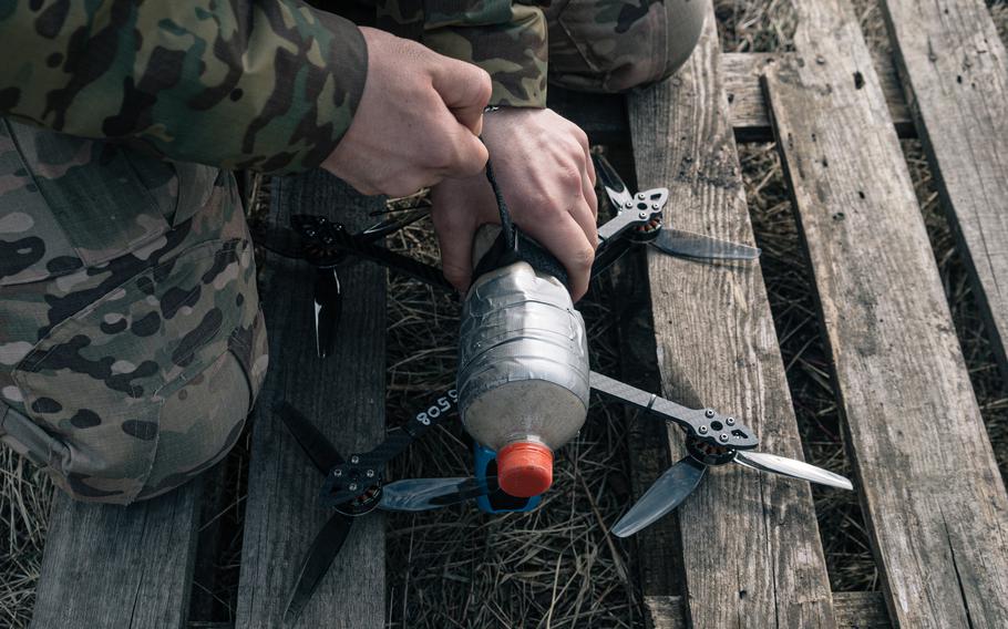 Denys straps a plastic bottle filled with sand to simulate the weight of a load of explosives onto an FPV drone for testing. 