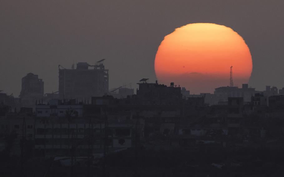 The sun sets behind the buildings in the Gaza Strip as seen from southern Israel, Saturday, June 29, 2024.