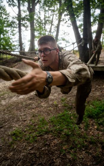 A Marine climbs a rope.