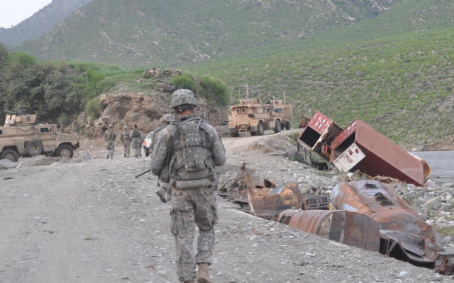 A soldier from A Company, 2nd battalion, 327th Infantry Regiment walks toward burned out tankers and supply trucks on the Kunar River road on Aug. 1, 2010.