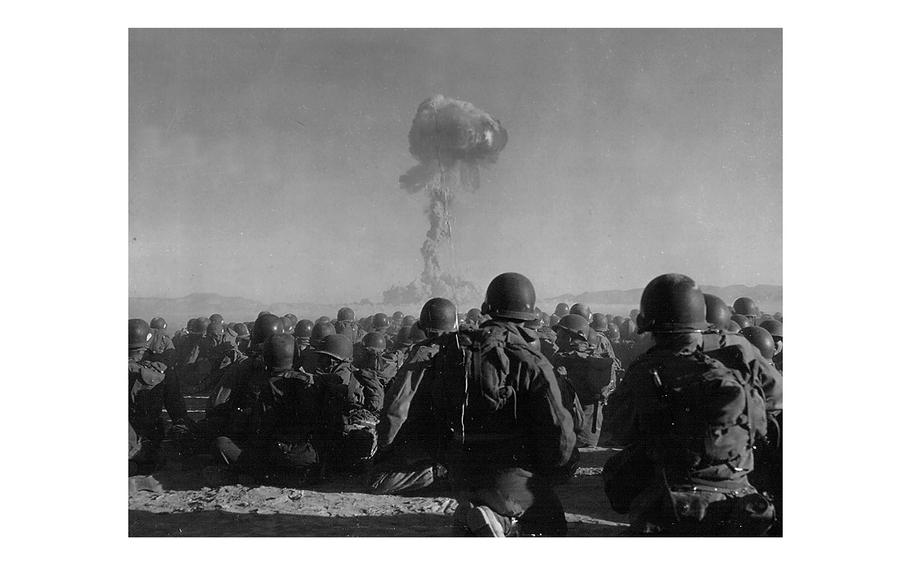 Troops of the U.S. Army 11th Airborne Division watch a plume of radioactive smoke rise on Nov. 1, 1951, after a blast at Yucca Flats, Nevada. 