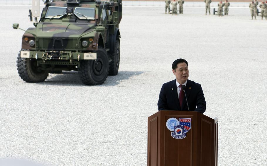 A South Korean official speaks at a podium with a military vehicle in the background.