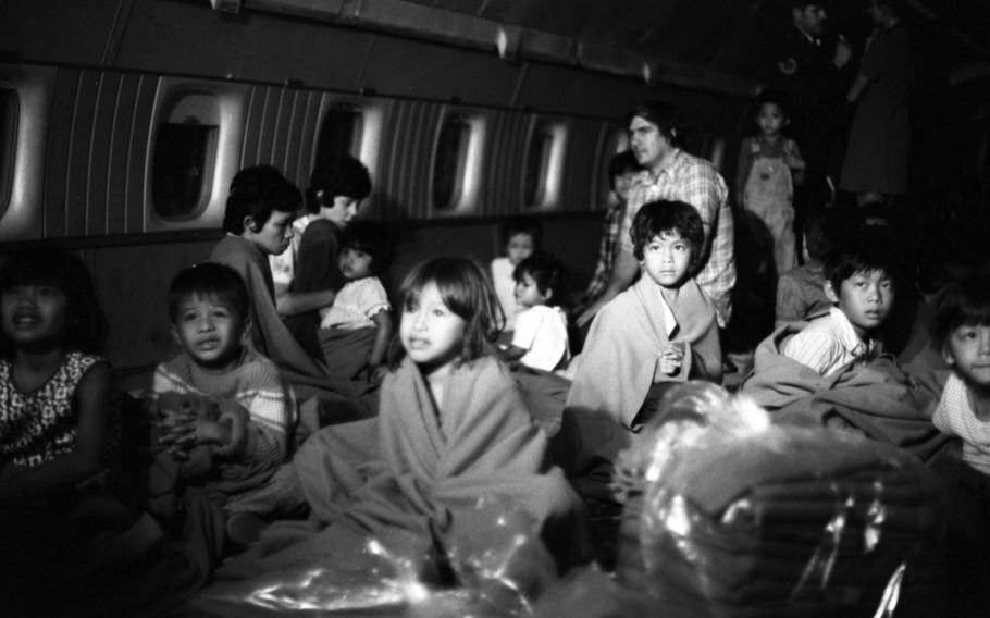 A black and white photo of children, many in blankets, inside of a plane.