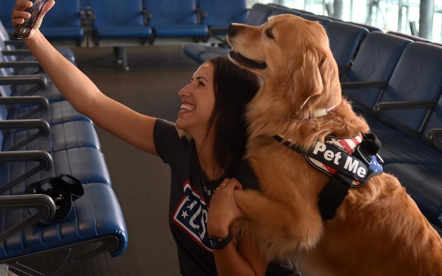 Ellie, a 7-year-old golden retriever and therapy dog, knows how to hug, a trick she practiced while getting a selfie with Beatriz Fracalosi, a USO center operations specialist and Air Force spouse on Oct. 18, 2023, at Ramstein Air Base, Germany.