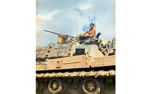 A shirtless man atop a tank.