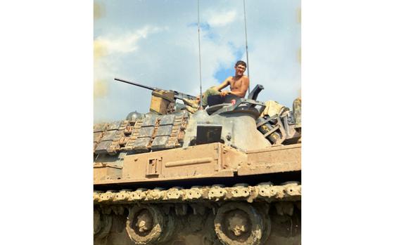 A shirtless man atop a tank.