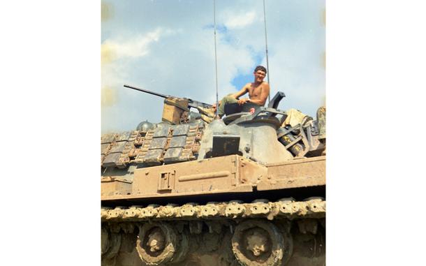 A shirtless man atop a tank.