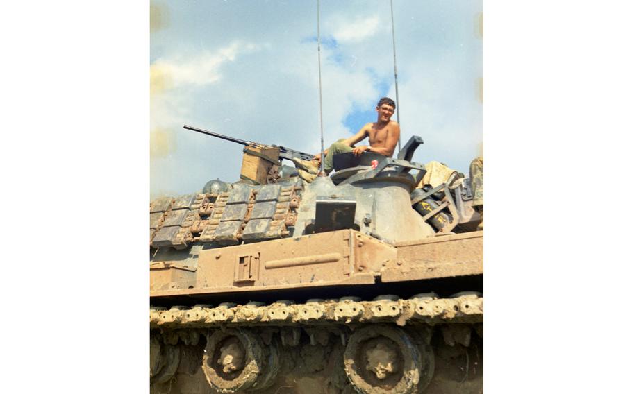 A shirtless man atop a tank.