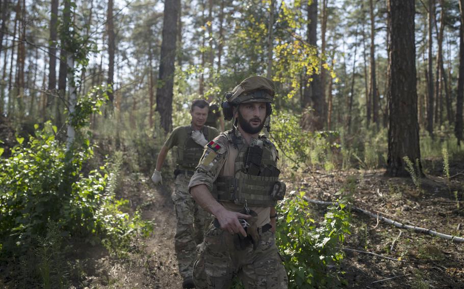 Ukrainian soldiers walk towards a howitzer position on the front line in the outskirts of Lyman, Ukraine, Tuesday, Aug. 15, 2023.