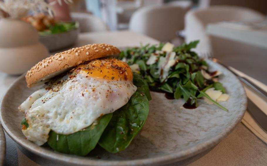The Veggie Lover bagel with a fried egg, tomatoes, spinach, avocado and gouda, served with a side of arugula and parmesan cheese at The Parlour in Landstuhl, Germany. The restaurant's signature version also comes with bacon.