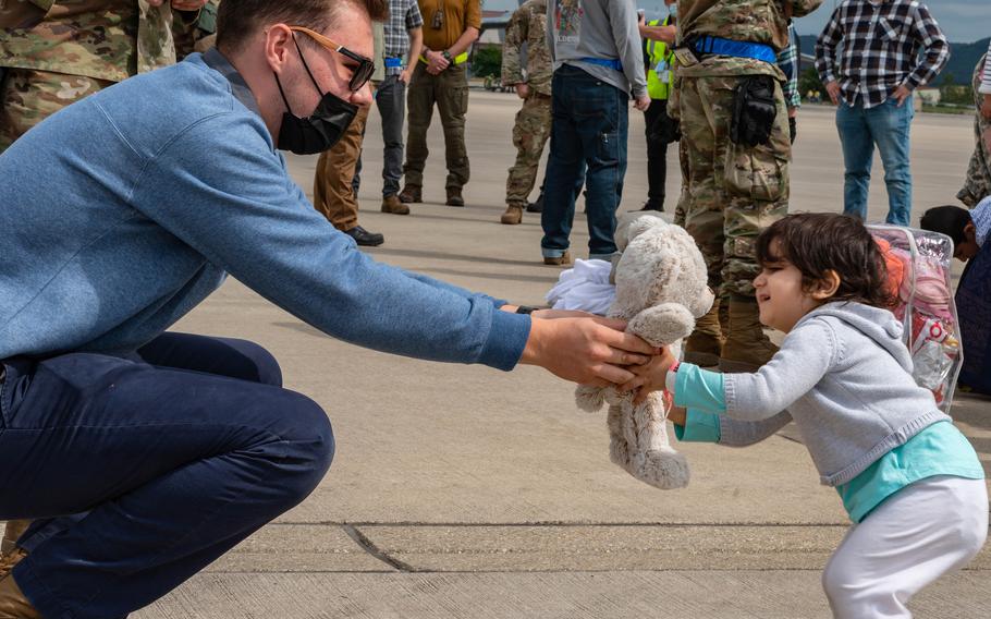 U.S. Air Force Airman Andrew Markos, 721st Aerial Port Squadron passenger service specialist, hands a Teddy bear to an Afghan evacuee at Ramstein Air Base, Germany, Aug. 24, 2021. U.S. airmen and volunteers have been working to deliver clothing, toys, water and other items to around 14,500 evacuees who have arrived at  Ramstein since August 17, 2021. 