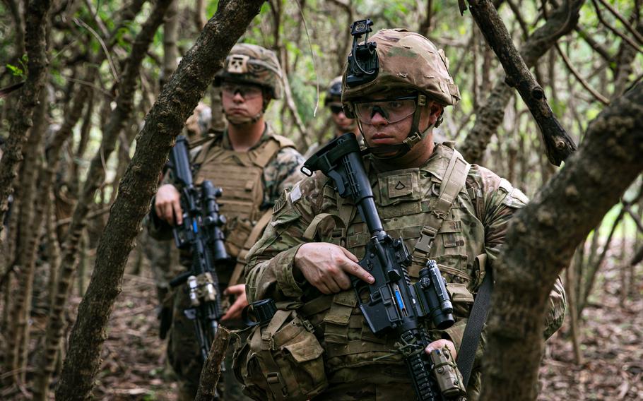 U.S. soldiers and Marines move through a Hawaiian jungle on Nov. 30, 2021, during a training meant to test short-notice deployment capabilities in the Indo-Pacific region.