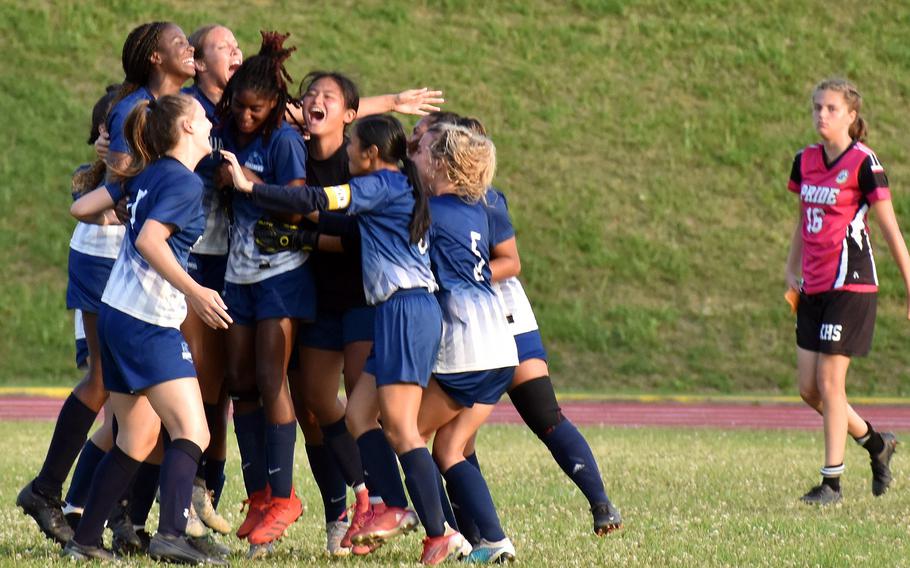 Guam High players celebrate while a dejected Marina Sawyer of Kadena looks on following Guam High's 1-0 double-overtime win in Tuesday's Division I girls soccer semifinal.