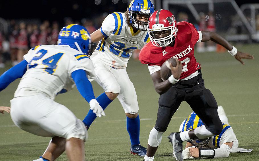 Nile C. Kinnick quarterback Josiah Chambers looks for room against Yokota defenders Dominik Citron and Josh Flores.