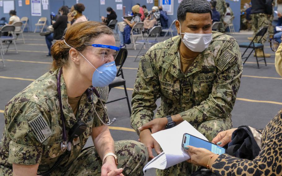 U.S. Navy Lt. Cmdr. Betsy Madison, left, a Boston native and a medical doctor assigned to Fort Belvoir Community Hospital, and U.S. Navy Boatswain Mate 1st Class Jean Guerra, a New York City native assigned to Mobile Diving and Salvage Unit 2, Joint Expeditionary Base Little Creek, Virginia, speak with a community member at the state-run, federally-supported Community Vaccination Center at York College in Brooklyn, New York, on March 10, 2021.