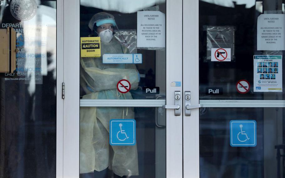 A staff member with personal protective equipment looks out from the front entry door of the Illinois Veterans'­ Home in LaSalle on Dec. 3, 2020.