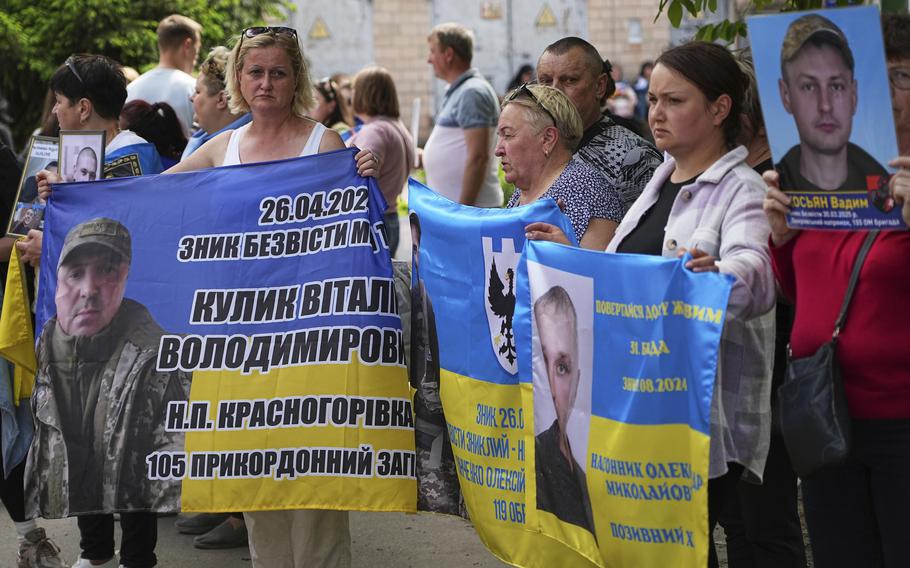 Ukrainians hold Ukrainian flags of their loved ones.