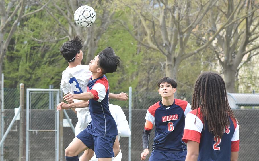 Sigonella's Alessandro Montero gets his head on the ball while battling Aviano's Keoni Andres on Saturday, April 15, 2023 as Saints Xavier Fox, center, and Andrew Walker watch.