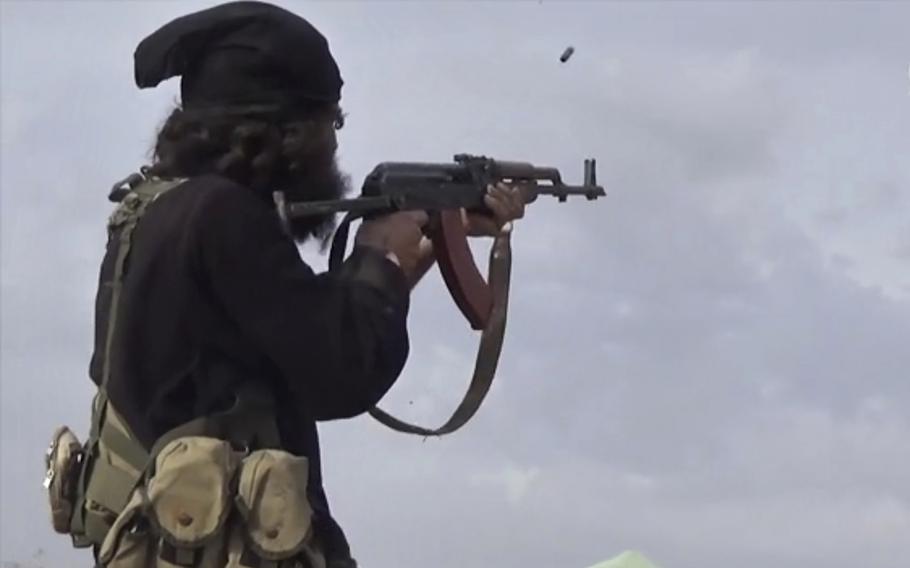 This file frame grab from video posted online March 18, 2019, by the Aamaq News Agency, a media arm of the Islamic State group, shows an ISIS fighter firing his weapon during clashes with the U.S.-backed Syrian Democratic Forces (SDF) fighters, in Baghouz, Syria.