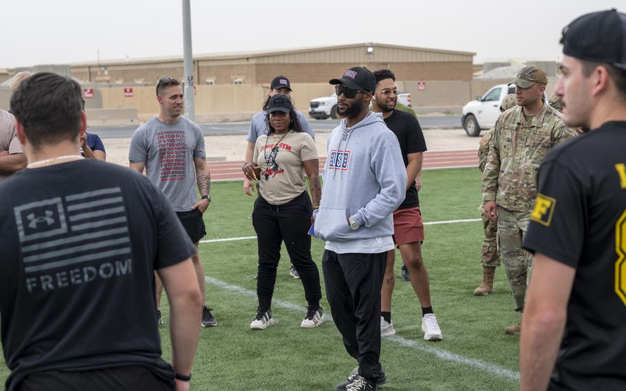 A NFL players speaks with airmen on a football field