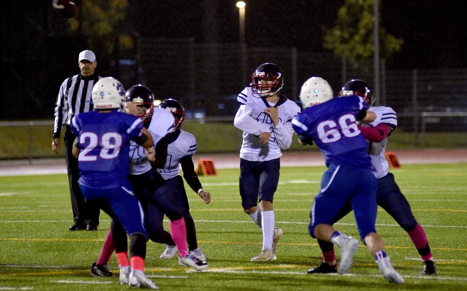 Lakenheath quarterback Nico Marchini throws as pass as Ramstein’s Ethan Wilson, left, and Ander Woodstock rush during Friday evening’s game in Ramstein, Germany.