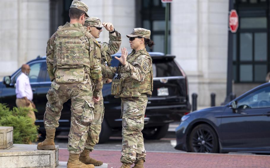 Three members of the National Guard talk to one another.