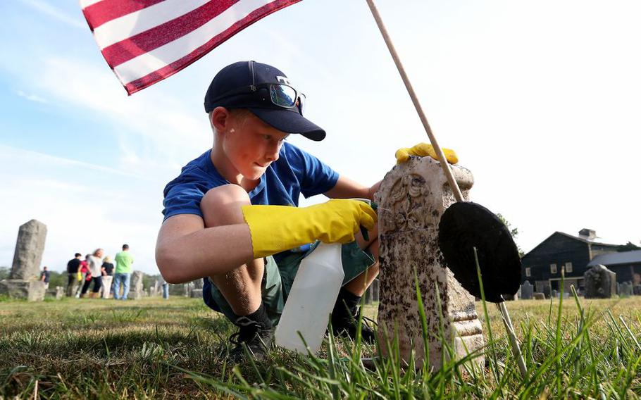 Volunteer Michael Piro, 11, of Frenchtown, cleans a headstone at Rosemont Cemetery in Delaware Township, N.J., on Aug. 21, 2022.