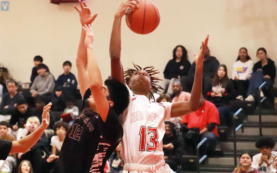 Matthew C. Perry's Daniel Rodriguez and Nile C. Kinnick's Jaelin White go up for a rebound during Saturday's DODEA-Japan boys basketball game. The Red Devils won 67-42.