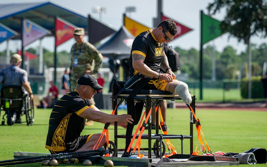 Sgt. 1st Class Joshua Olson helps retired Army Staff Sgt. Jason Smith onto a seated platform during a Warrior Games practice session at the ESPN Wide World of Sports Complex in Orlando, Fla., Aug. 19, 2022. 