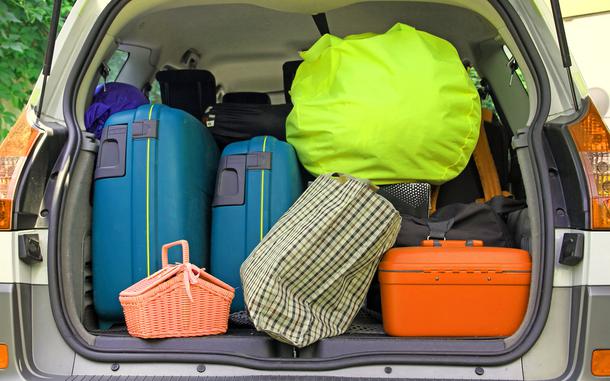 twosuitcases and many bags in the trunk of the car ready to depart