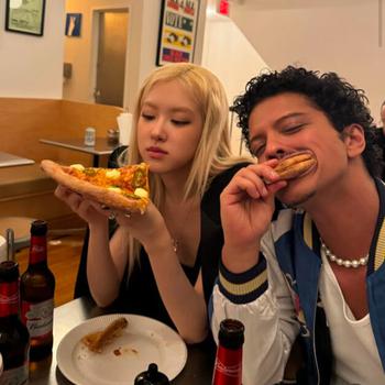 A blond woman and dark-haired man eat pizza.
