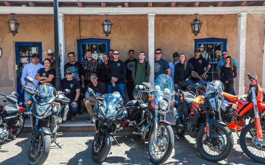 People stand together behind motorcycles.