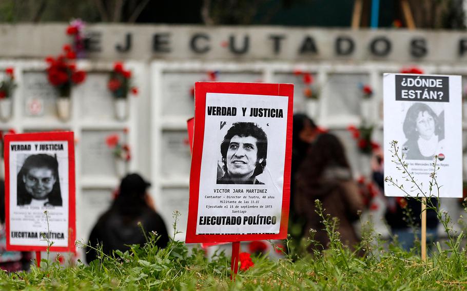 A poster with a picture of teacher and singer Victor Jara, who was tortured and shot to death during the Chilean dictatorship, is seen as people demonstrate at the General Cemetery during the commemoration of the 49th anniversary of the 1973 military coup d’etat of Augusto Pinochet and subsequent death of President Salvador Allende, in Santiago, on Sept. 11, 2022.