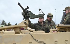 A German Army NCO School candidate checks out the machine gun mounted atop an M1064A3 light armored vehicle during an exchange with U.S. soldiers in Grafenwoehr, Germany, on Feb. 22, 2024.