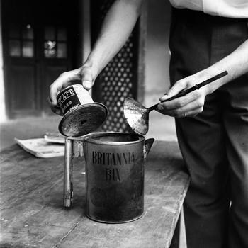 A person’s hands hold parts of a makeshift pot or kettle.