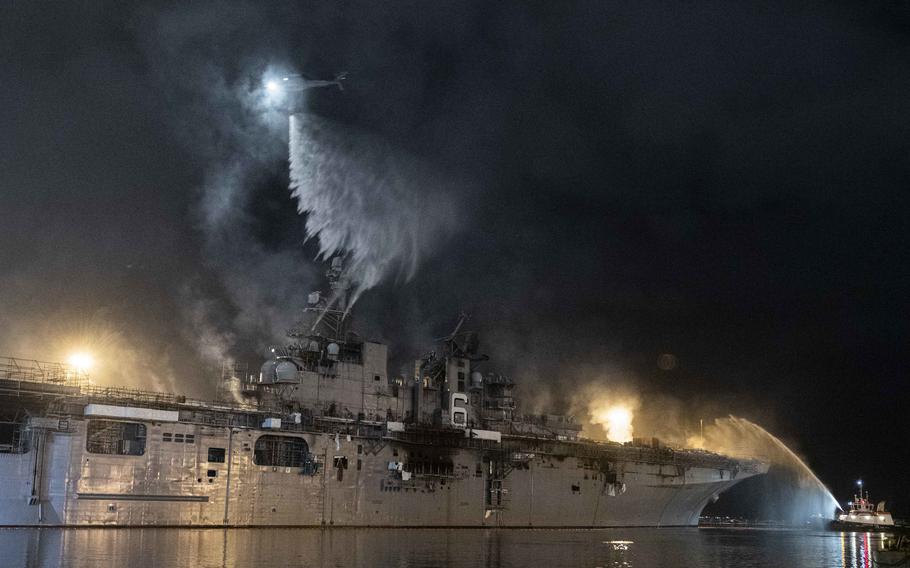 A helicopter from Helicopter Sea Combat Squadron 3 combats a fire aboard the amphibious assault ship USS Bonhomme Richard at Naval Base San Diego, July 14, 2021.  Navy investigators cited the lack of a fire main on the Naval Base San Diego pier where the amphibious assault ship Bonhomme Richard was moored as one of several obstacles firefighters encountered upon first responding to the inferno. 