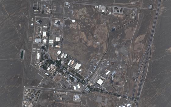An overhead satellite image shows a nuclear facility with several buildings spread out in a desert setting.