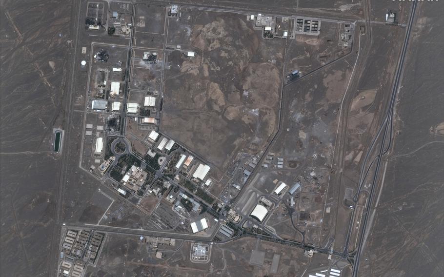 An overhead satellite image shows a nuclear facility with several buildings spread out in a desert setting.