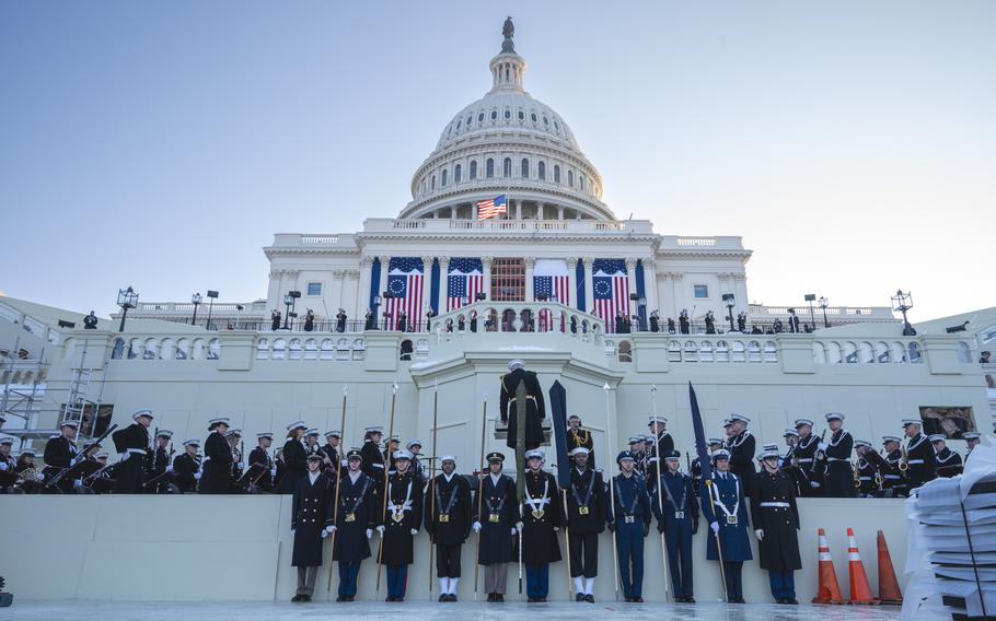 Personnel in decorative uniforms line the ramparts of the U.S. Capitol.