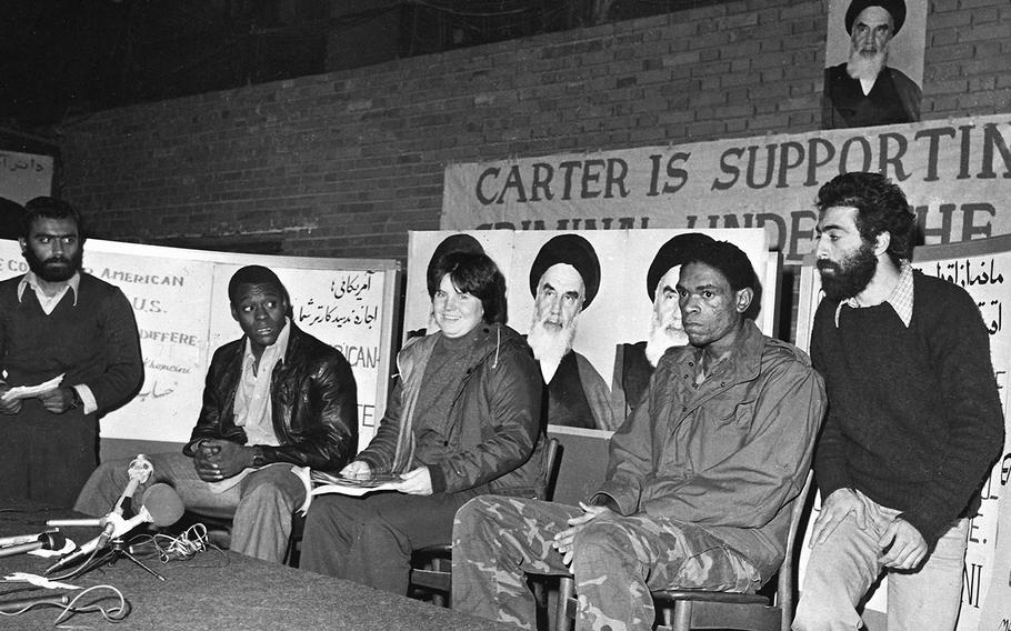 Three unidentified U.S. hostages speak to the media, while flanked by Iranian captors, at the besieged U.S. embassy in Tehran in  November 1979. 