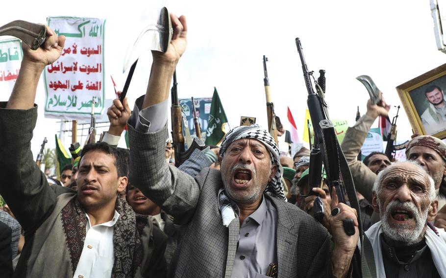 Men raise hands and guns and shout.