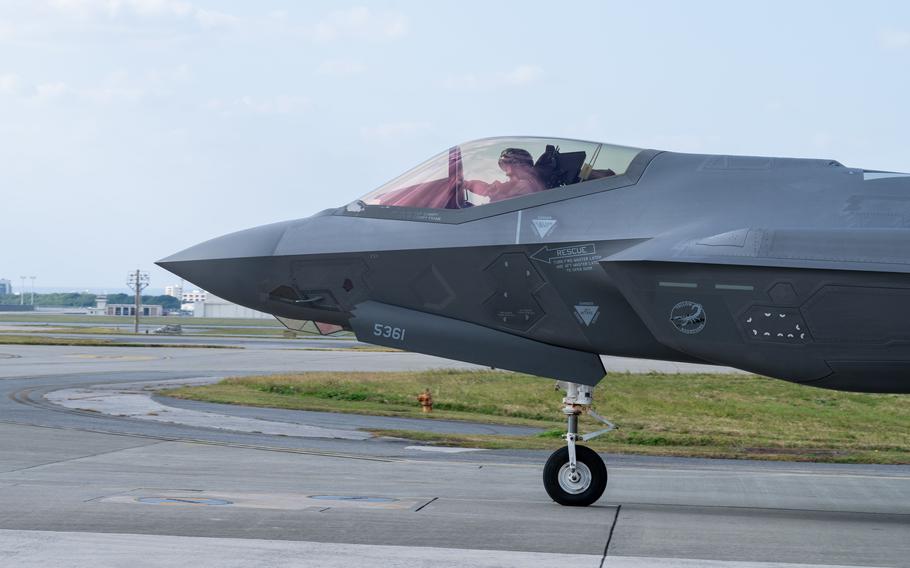 A front half of a military fighter jet is seen from the side as it taxis on a runway.