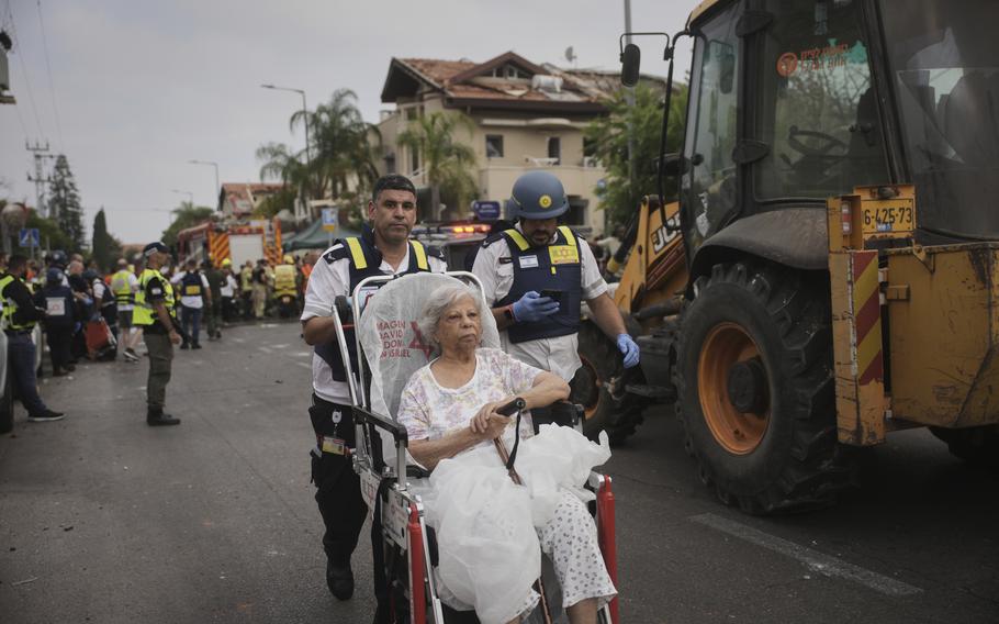 Paramedics evacuate a woman in a wheelchair.