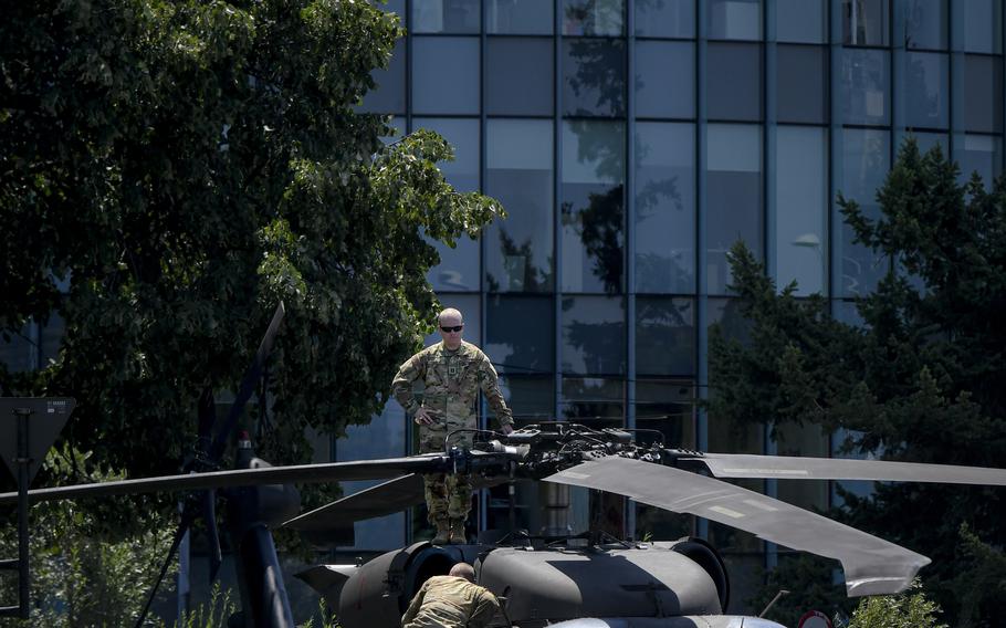 A U.S serviceman inspects the blades of an U.S military Black Hawk helicopter following an emergency landing on a busy boulevard in Bucharest, Romania, Thursday, July 15, 2021. 