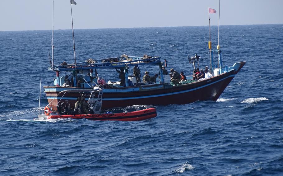 Coast Guardsmen pull their boat next to a stateless vessel in the Arabian Sea.