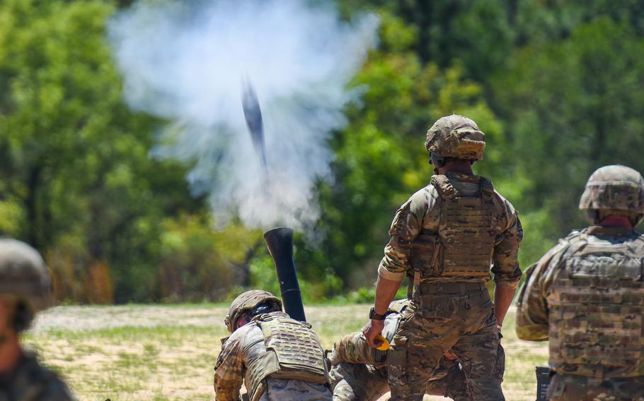 Smoke flashes as soldiers fire a mortar.