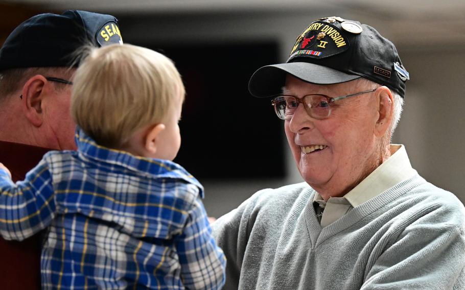 World War II veteran Don Halverson greets his one-year-old great grandson, Henry Halverson, held by his grandfather, Gordy Peterson, during a party to celebrate the elder Halverson's 100th birthday at the Crystal VFW Post 494 on Friday, Feb. 24, 2023. Halverson served in Italy from 1943-45 as part of Minnesota's 34th Red Bull Infantry Division.