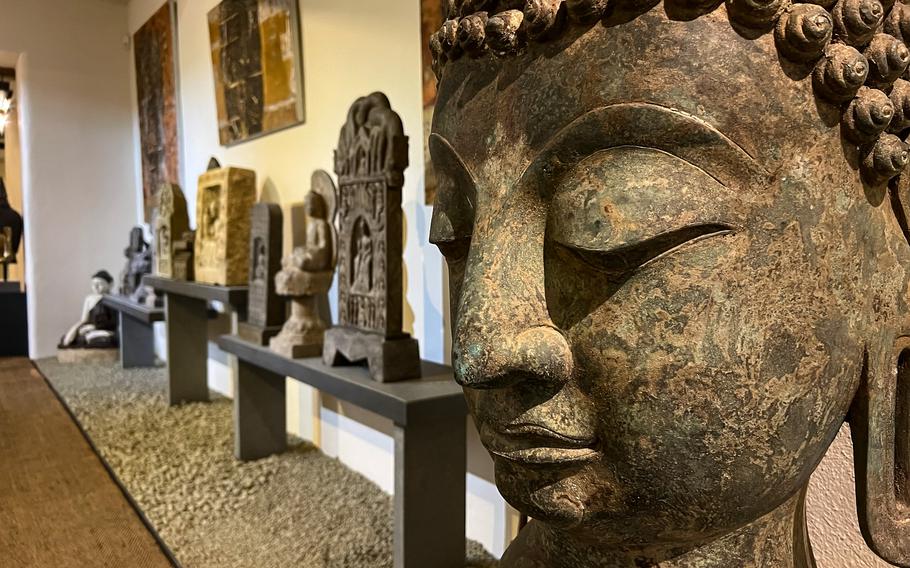 A Buddha bust in the basement at the Buddha Museum in Traben-Trarbach, Germany, June 11, 2022. The large open basement offers Buddha steles and statues from Thailand, Cambodia, China and Japan and shows off the building's wine-cellar origins, with large intake spouts once used for wine production still visible.